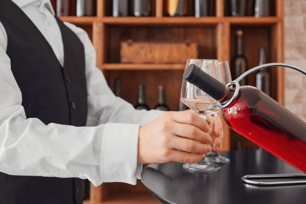 Sommelier se sklenicemi a lahví vína na držáku ve sklepě - Fotografie, Obrázek