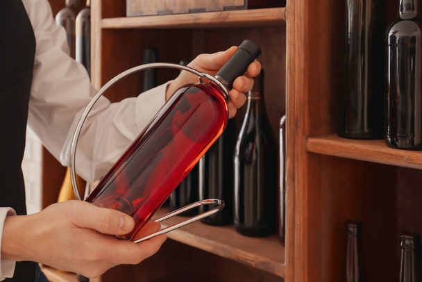 Sommelier με μπουκάλι κρασί για τον κάτοχο στο κελάρι - Φωτογραφία, εικόνα