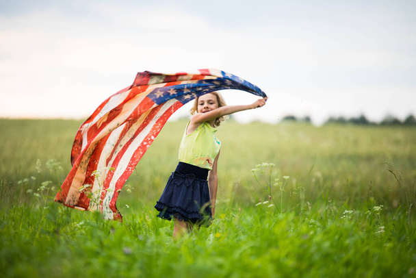 Patriotic holiday. Happy kid, cute little child girl with American flag. - Foto, immagini