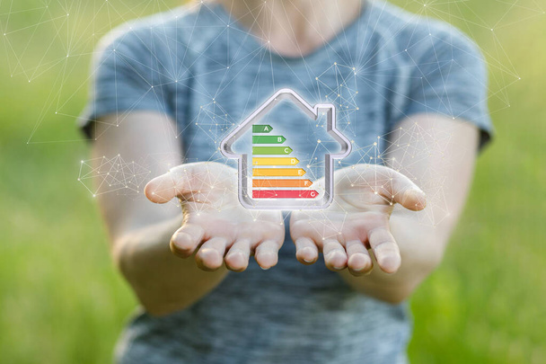 Energieeffizientes Wohnkonzept. Eine Frau zeigt ein Modell eines Energiesparhauses. - Foto, Bild