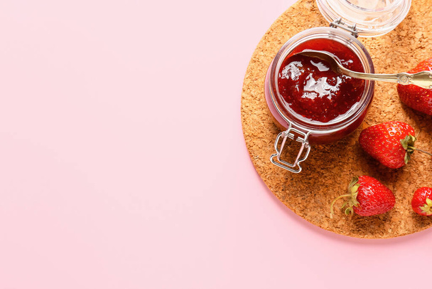 Tarro de sabrosa mermelada de fresa sobre fondo de color
 - Foto, imagen