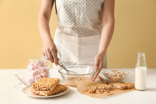 Жінка готує хрусткі рисові батончики за столом
 - Фото, зображення