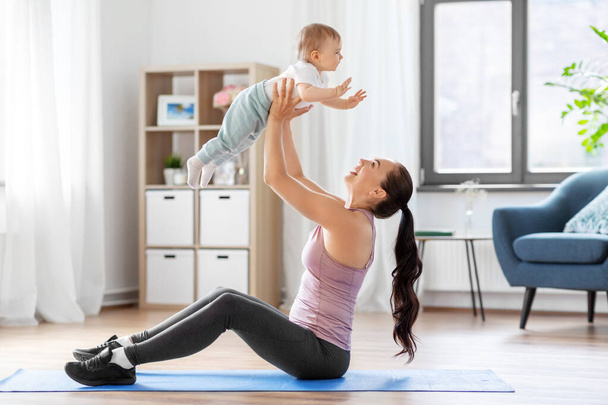 happy mother with little baby exercising at home - 写真・画像