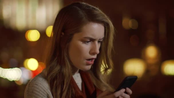 Järkyttynyt tyttö kasvot lukeminen SMS puhelin ulkona. Järkyttynyt nainen saa viestin puhelin - Materiaali, video