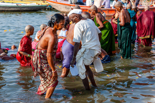 インド、バラナシ州- 2011年4月23日:ガンガ川で儀式用の風呂に入る未確認の人々。毎日神事風呂が開催されます - 写真・画像
