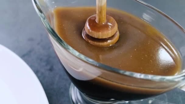 El jarabe dulce se vierte con un cazo de miel o un palo. Palillo de miel en un frasco con líquido marrón
. - Imágenes, Vídeo