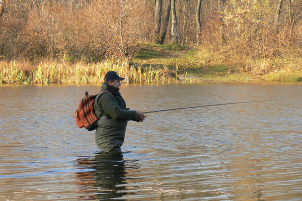 ένας άνθρωπος στέκεται στο νερό και πιάνει ψάρια γυρίζοντας - Φωτογραφία, εικόνα