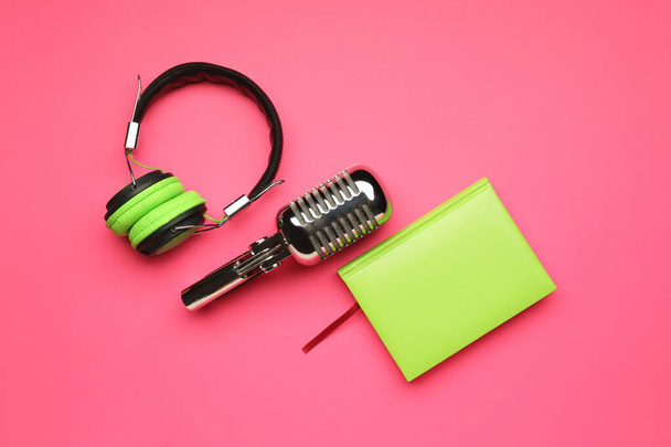 Headphones with microphone and notebook on color background - Photo, Image