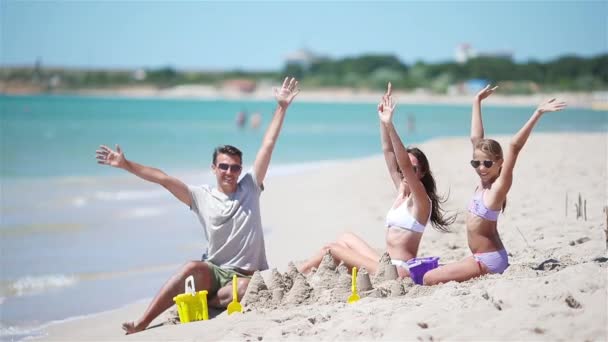 Padre e figli che costruiscono un castello di sabbia sulla spiaggia tropicale. Famiglia che gioca con i giocattoli da spiaggia - Filmati, video