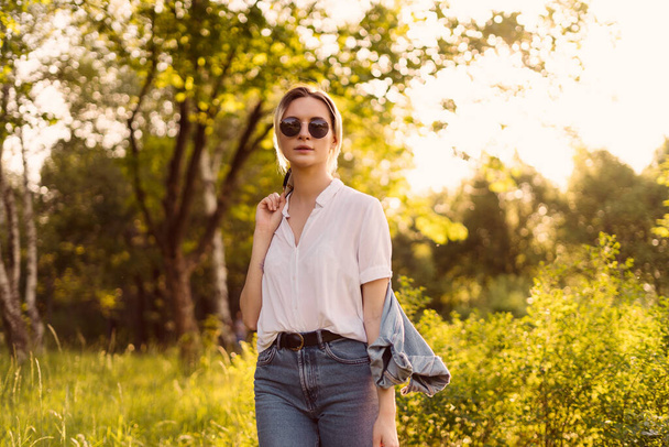 Kobieta w okularach przeciwsłonecznych spacerująca po parku - Zdjęcie, obraz