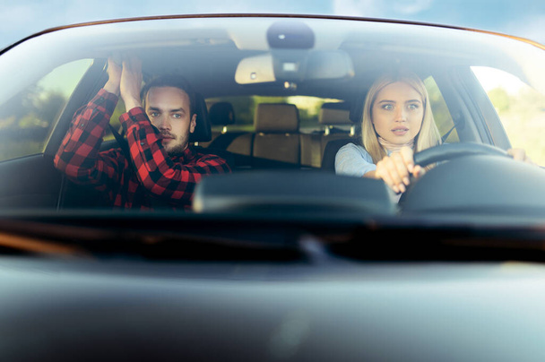 Rémült nő és oktató az autóban, elől, autósiskolában. Férfi tanítja a hölgyet autót vezetni. Jogosítvány oktatás, baleset - Fotó, kép
