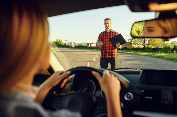 Woman in the car, instructor with checklist on road, driving school. Man teaching lady to drive vehicle. Drivers license education - Photo, Image
