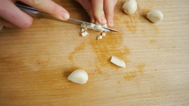 Taglia l'aglio con un coltello. La donna taglia gli spicchi d'aglio su piccoli pezzi. - Filmati, video