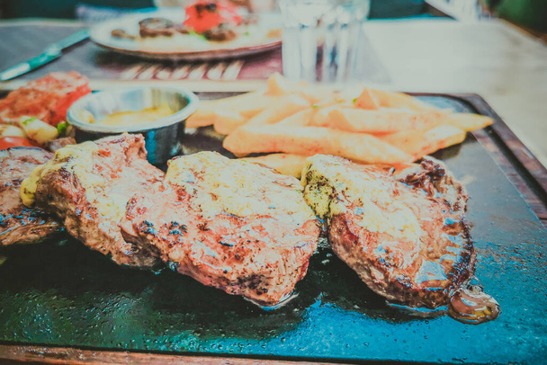 Pihvi ja perunat lautasella ruoan taustalla
 - Valokuva, kuva