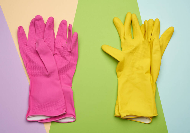 twee paar beschermende rubberen handschoenen op een gekleurde achtergrond, bovenaanzicht, platte lay - Foto, afbeelding