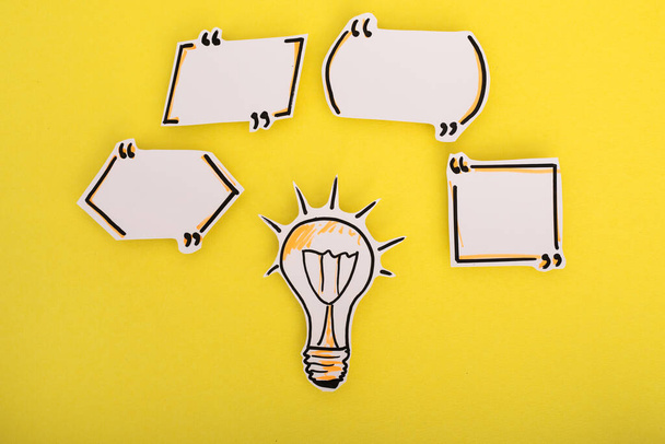 Paper speech bubbles and bulb icon on the yellow - Foto, afbeelding