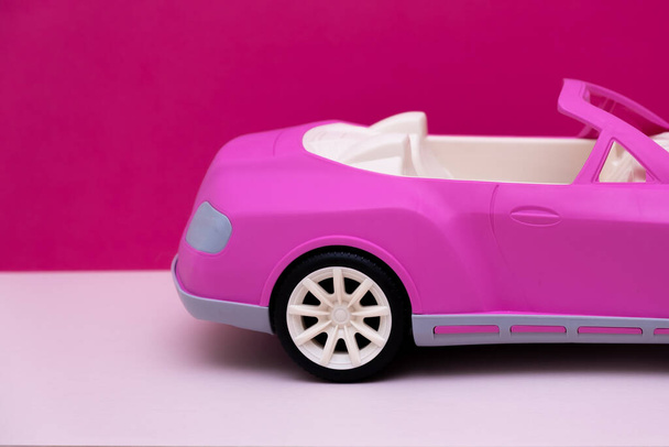 roze auto op een roze achtergrond. Concept van autoverkoop, autoverhuur of autoverhuur. - Foto, afbeelding