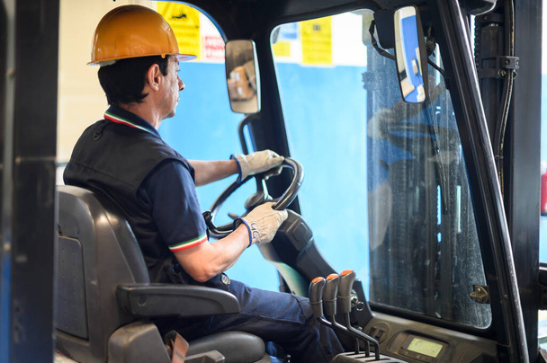 Un ouvrier de la construction conduisant un chariot élévateur dans une usine industrielle - Photo, image