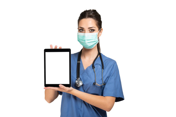 Masked young nurse doctor using a tablet, isolated on white - Foto, immagini