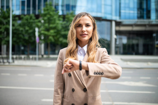 Confident young female manager checking the time on her watch outdoor - Foto, Bild