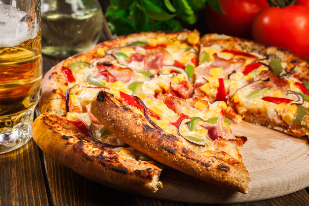 Homemade pizza with bacon, paprika and corn served on a wooden board - Foto, Bild