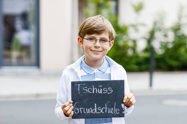 Happy little kid boy with backpack or satchel and glasses. Schoolkid on the way to school. Healthy adorable child outdoors On desk Bye elementary school in German. Schools out - Photo, Image