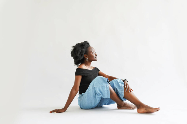 african woman dressed in casuals sitting on white - Foto, Imagem