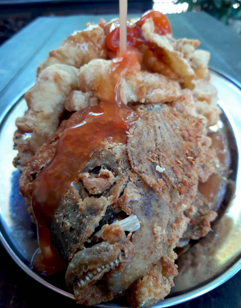 Kořeněná omáčka se nalije na porci křupavé smažené ryby na talíři jako doplněk k ochucení - Fotografie, Obrázek