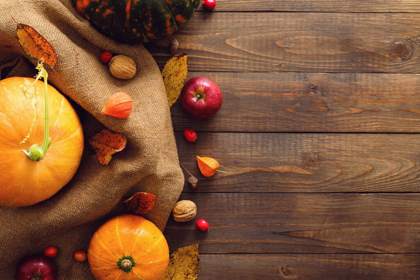 Autumn background with fallen leaves, fabric and pumpkins on rustic wooden table. Thanksgiving day concept. Flat lay, top view, copy space. - Photo, image