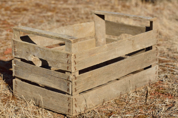 Una caja vacía de madera usada para frutas o verduras, se encuentra en un prado seco seco en el verano en el sur en calor
 - Foto, Imagen