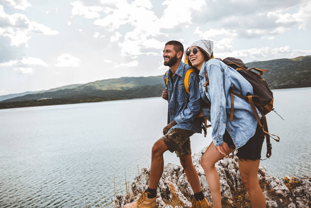 Туристи з рюкзаками на скелі насолоджуються гірським озером
 - Фото, зображення