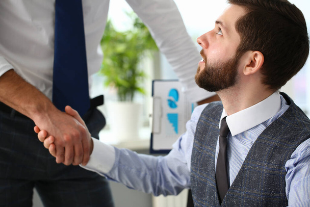 Takım elbiseli ve kravatlı bir adam iş arkadaşıyla el sıkışıyor. - Fotoğraf, Görsel