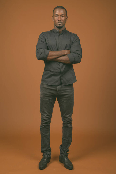 Stúdió lövés jóképű afrikai üzletember visel fekete ing ellen barna háttér - Fotó, kép