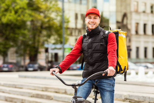 livreur gars souriant à caméra posant avec vélo dans la ville - Photo, image