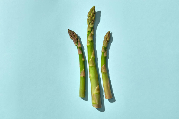 Tres lanzas de espárragos verdes sobre fondo rosa. Concepto de cosecha de alimentos saludables y verduras de temporada. Cerrar, copiar espacio
 - Foto, imagen