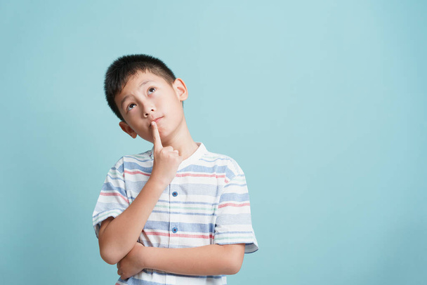 Asian little boy standing thinking on blue background isolated, Asia man look up and copy space	 - Fotoğraf, Görsel