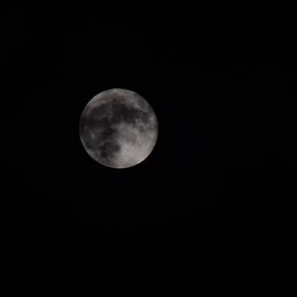 Super Lune dans la nuit noire derrière les nuages, la lune se cache derrière les nuages pendant la nuit - Photo, image