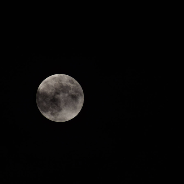 Super Lune dans la nuit noire derrière les nuages, la lune se cache derrière les nuages pendant la nuit - Photo, image