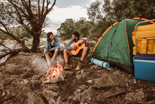 Romantisches Paar am Lagerfeuer. Schönes verliebtes Paar genießt auf Campingplatz. - Foto, Bild