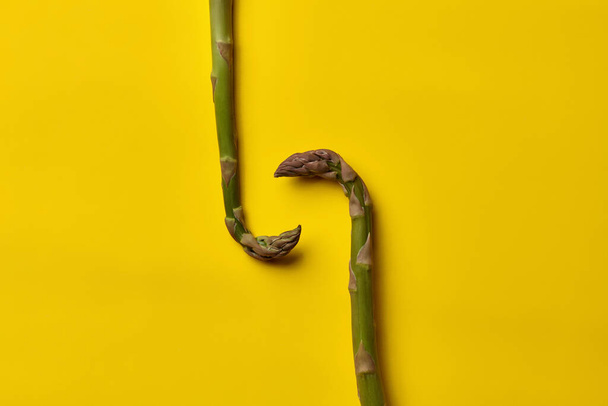 Duas lanças de espargos verdes não cozidas no fundo amarelo. Nutrição saudável, alimentação e colheita sazonal de vegetais. Fechar, espaço de cópia
 - Foto, Imagem