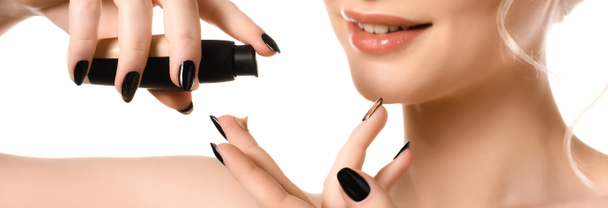 vue recadrée d'une femme nue souriante aux ongles noirs qui applique un fond de teint sur les doigts isolés sur une photo panoramique blanche - Photo, image