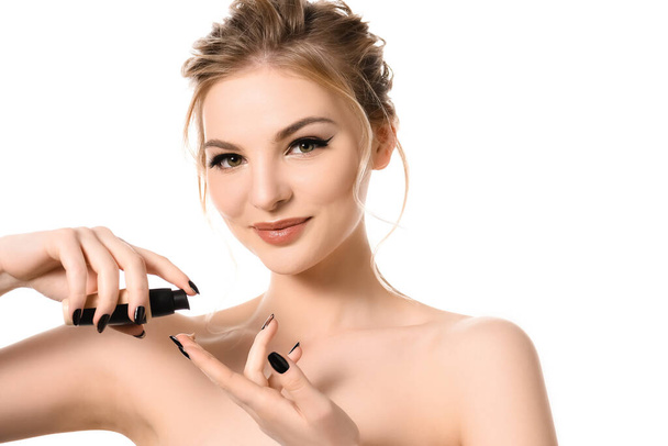 smiling naked beautiful blonde woman with makeup and black nails applying face foundation on fingers isolated on white - Photo, Image