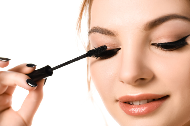 mooie vrouw met make-up en zwarte nagels aanbrengen mascara geïsoleerd op wit - Foto, afbeelding