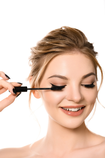 smiling naked beautiful blonde woman with makeup and black nails applying mascara isolated on white - Photo, image