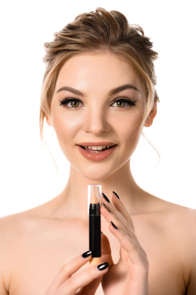 naked beautiful blonde woman with makeup and black nails looking at stick concealer isolated on white - Foto, immagini