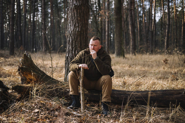 Tough manhood forester sitting on the felled tree trunk in brown clothes - Photo, Image