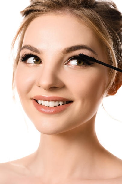 χαμογελαστή όμορφη ξανθιά γυναίκα εφαρμογή μάσκαρα απομονωμένη σε λευκό - Φωτογραφία, εικόνα