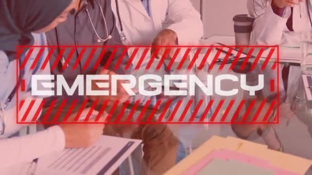 Animation of a red sign with white word EMERGENCY over a mid section view of of male and female healthcare workers discussing in hospital. Coronavirus Covid-19 pandemic concept digital composite. - Filmati, video
