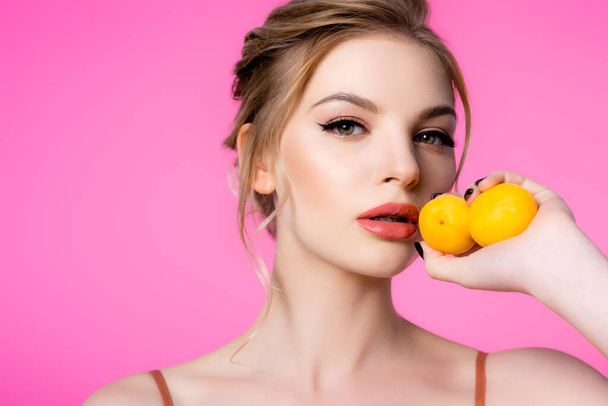 elegant beautiful blonde woman holding apricots isolated on pink - Photo, Image