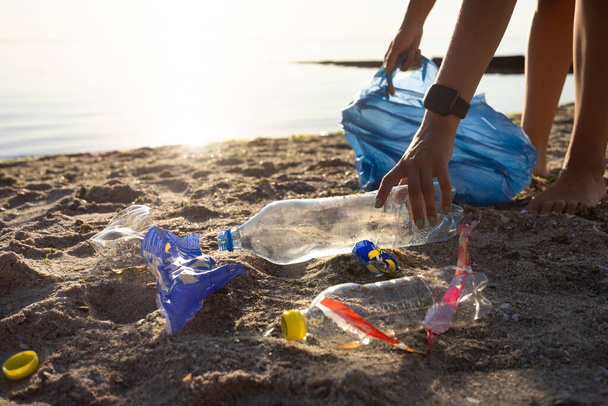 Naispuolinen vapaaehtoinen puhdistus saastunut ranta kerääminen muovi roskakoriin ulkona, rajattu - Valokuva, kuva